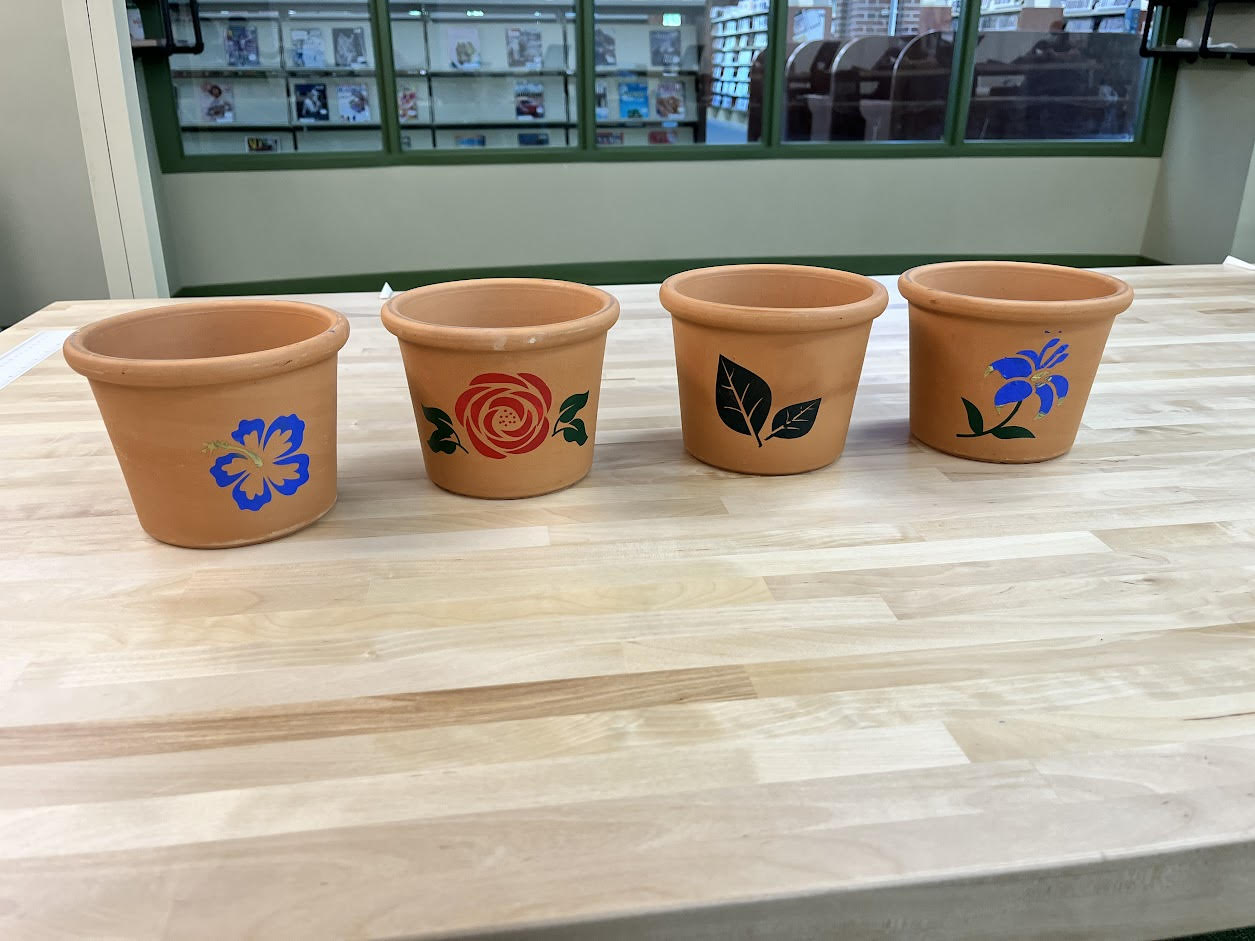 A set of four flower pots with plants painted on them.