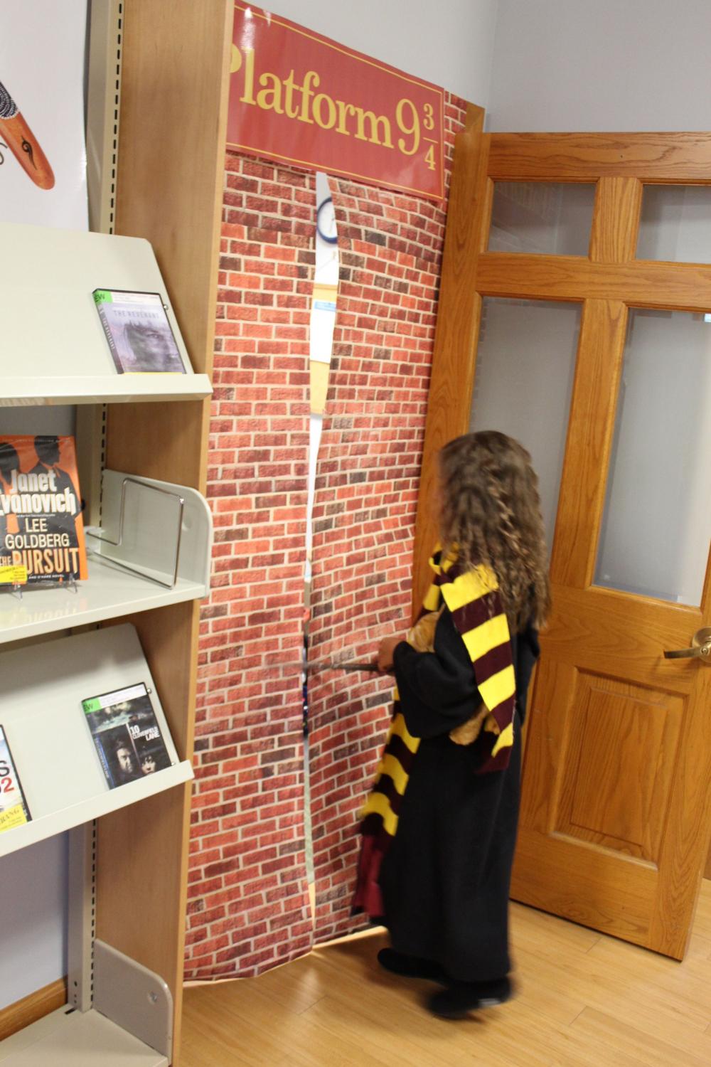 A girl points her wand through Platform 9 and three-quarters during Harry Potter Day