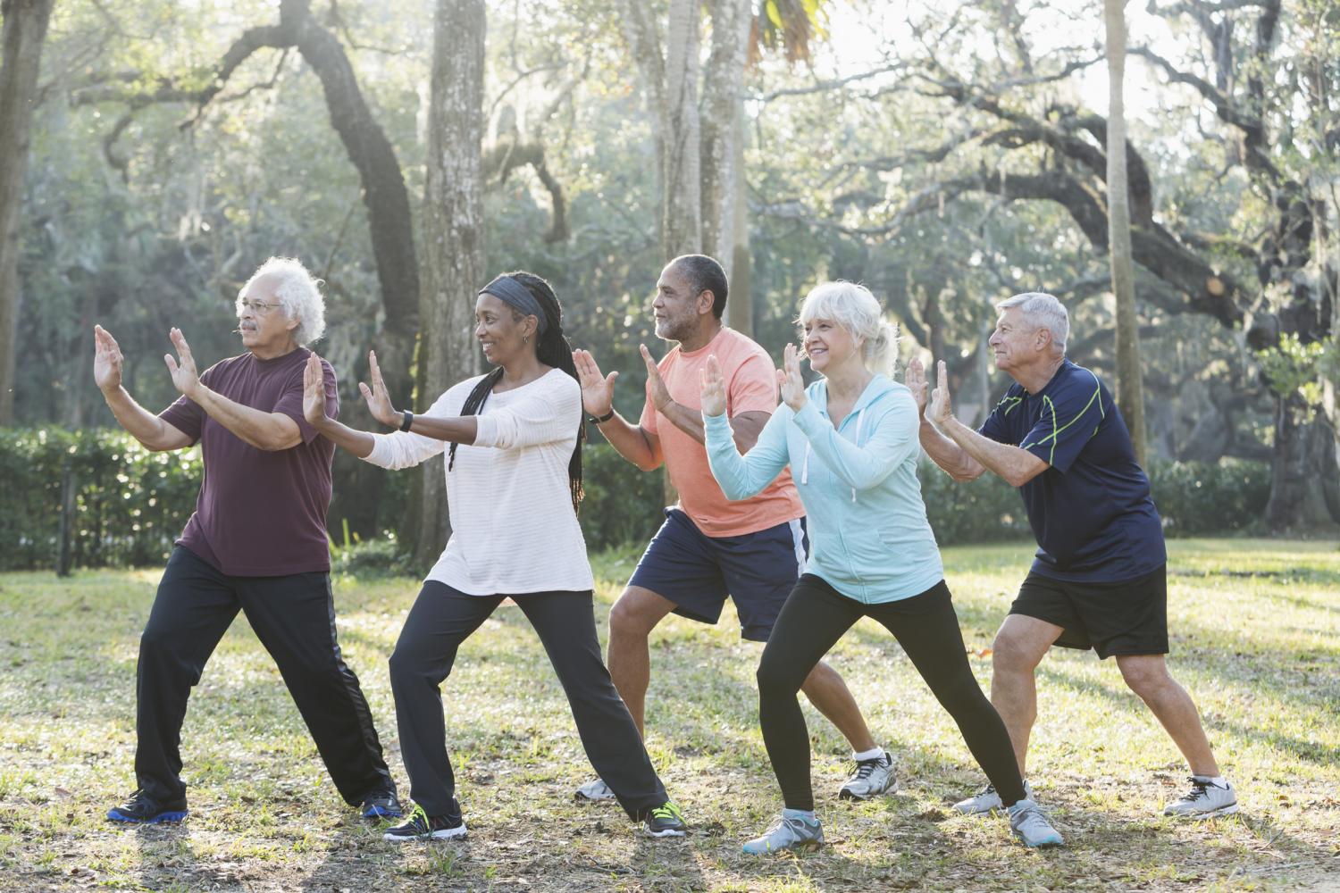 a group of adults doing tai chi moves outside