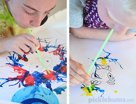 Child blowing through a straw to use watercolor paint