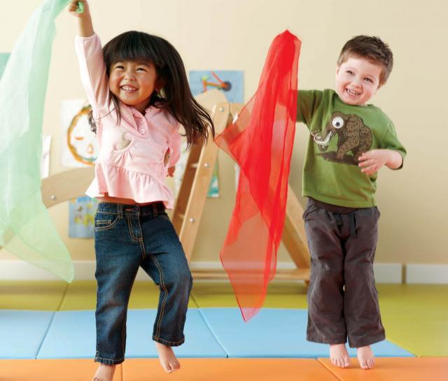 Girl and boy toddlers dancing with scarves in the air