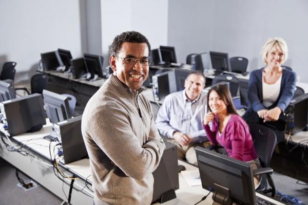 man working with other adults in a computer lab
